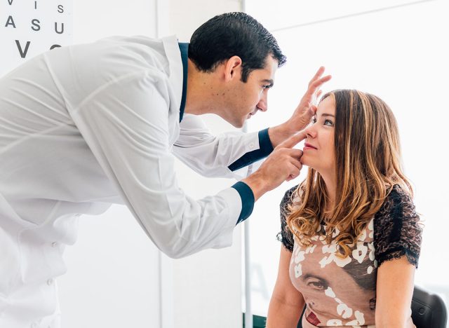 optometry concept - pretty young woman having her eyes examined by an eye doctor