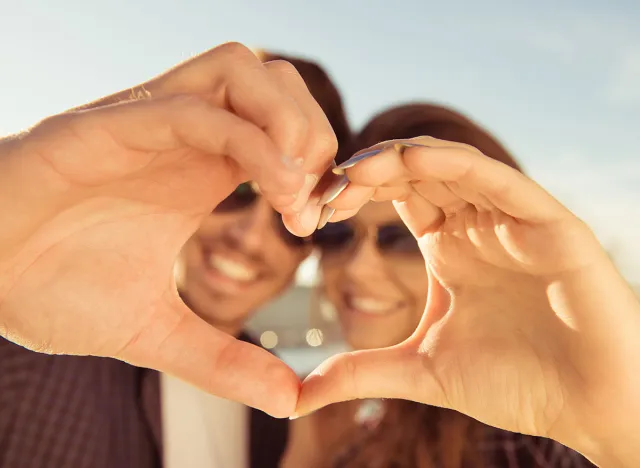 Happy romantic couple in love gesturing a heart with fingers