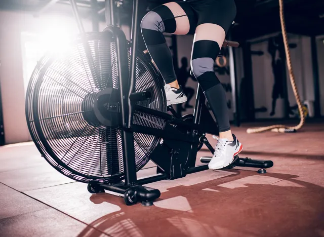 Shot of athlete woman exercising on assault air bike.