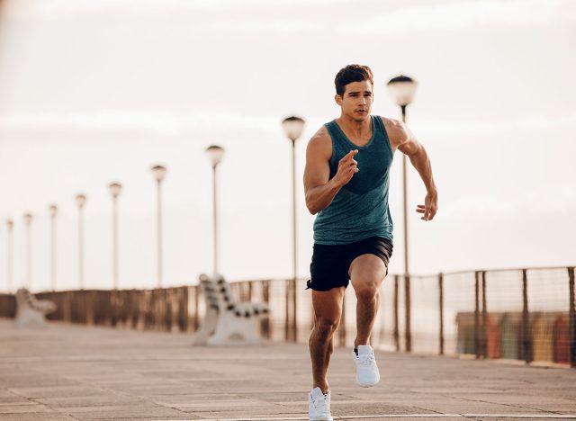 Full length shot of healthy young man running on the promenade. Male runner sprinting outdoors.