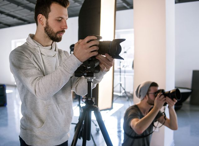 Creative photographers work in studio. Two people with cameras during the studio session. Creative photo and video team shooting in interior