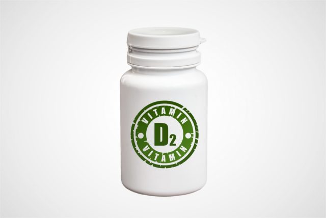 Bottle of pills with vitamin D2 on white background