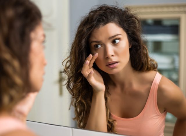 Tired woman looking her eye bags in the bathroom.