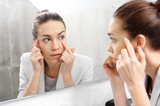 Woman looking at her reflection in the mirror.