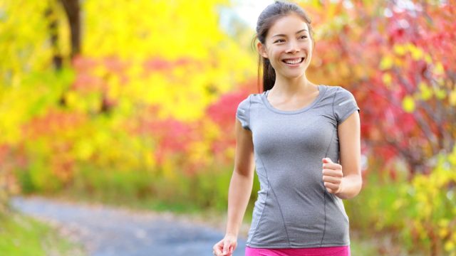 Woman power walking nordic speed walk and jogging and running lightly in forest in spring or summer. Sport fitness girl sports training and working out living healthy active lifestyle in forest.