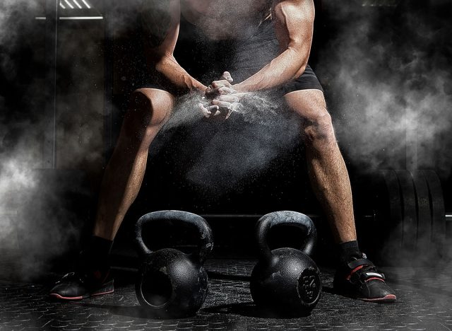 Weightlifter clapping hands and preparing for workout at a gym. Focus on dust