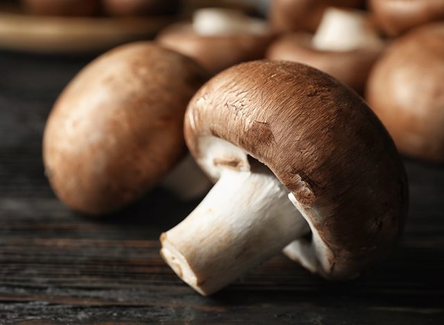 Fresh champignon mushrooms on wooden table, closeup. Space for text