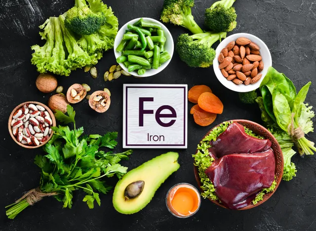 Food containing natural iron. Fe: Liver, avocado, broccoli, spinach, parsley, beans, nuts, on a black stone background. Top view.