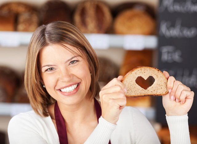 Happy woman showing bread with heart shape