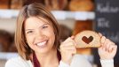 Happy woman showing bread with heart shape