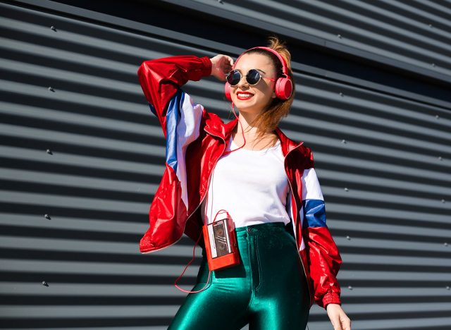 Back in time 90s 80s. Stylish girl in retro jacket and vintage cassette player listens to music, fashion trends, entertainment, heat in summer