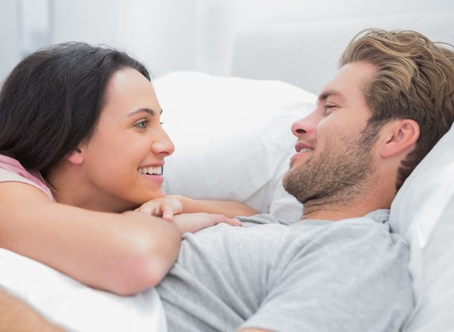 Cheerful couple awaking and looking at each other in bed