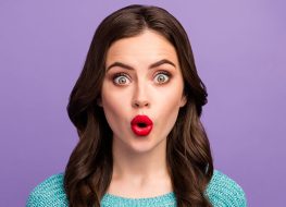 Closeup photo of beautiful pretty curly lady red lips o shape good mood listen amazing news open mouth wear casual blue knitted sweater isolated purple color background