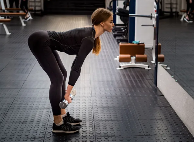 Beautiful woman performs Romanian deadlift in gym