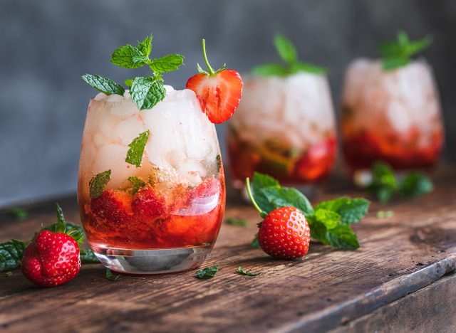 Fresh strawberry mojito drinks. There are three drinks on a vintage wooden dark table. The cocktails or mocktails are decorated with strawberries and fresh mint. Copy space room for text.