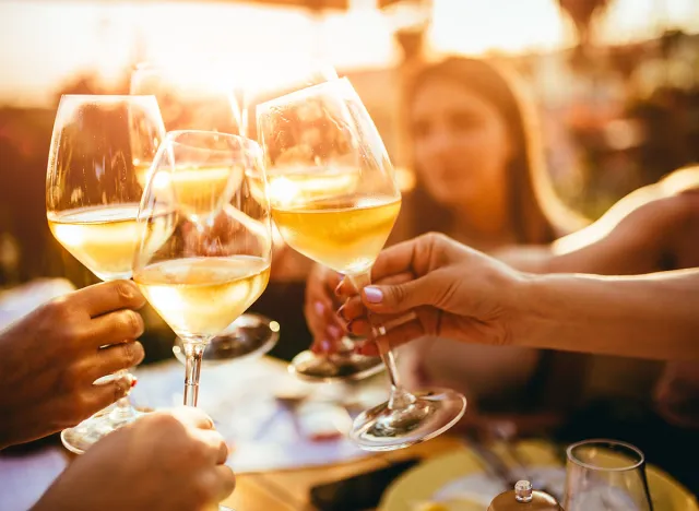 People clinking glasses with wine on the summer terrace of cafe or restaurant