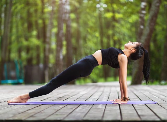 Female trainer in sportswear, practicing yoga asanas, doing the reverse plank