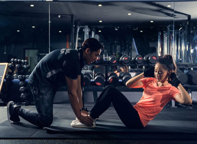 Personal trainer to practice sit-ups in the gym