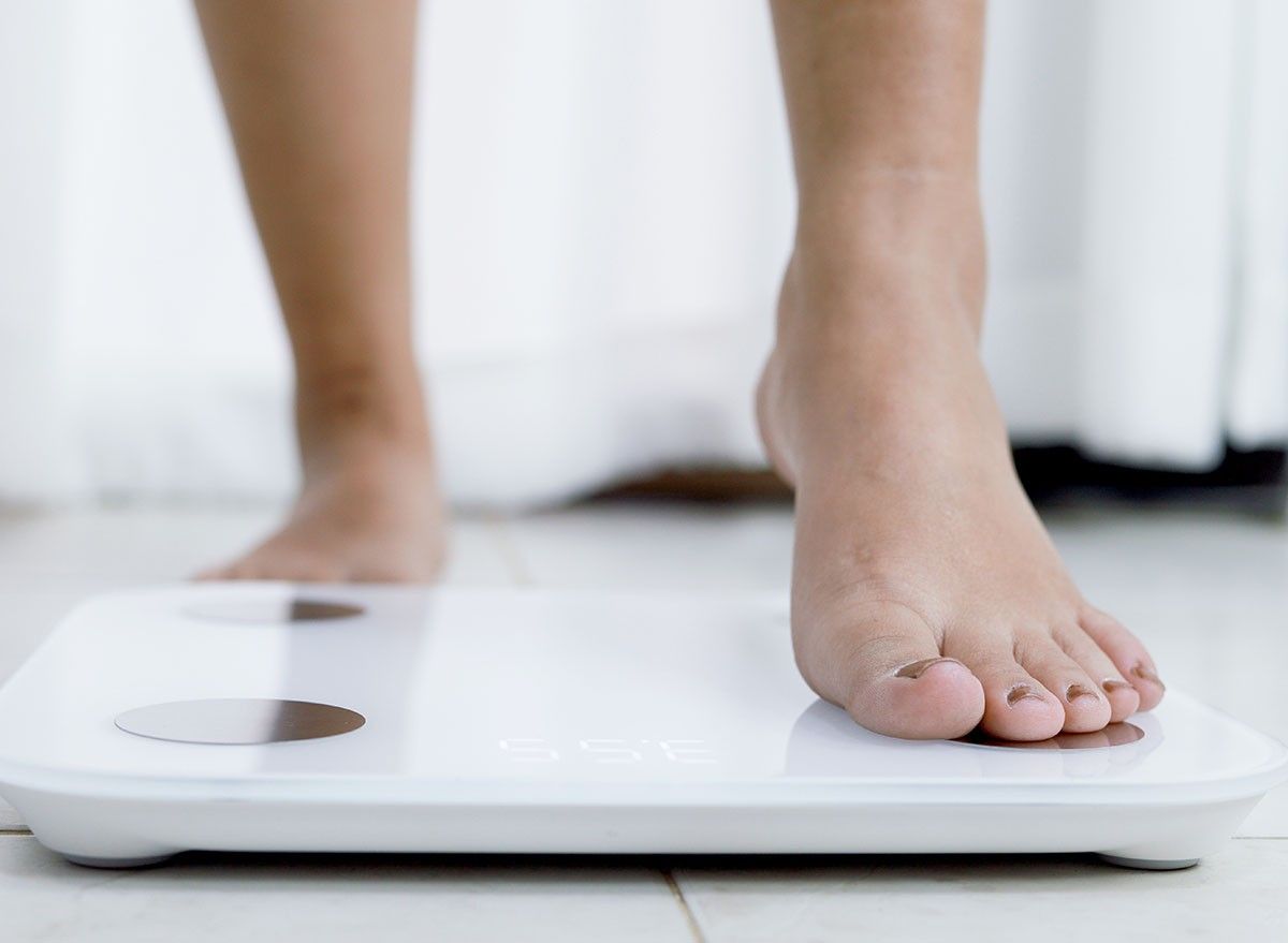 feet standing on electronic scales for weight control. Measurement instrument in kilogram for a diet control