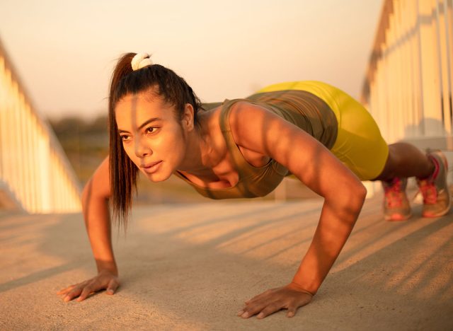 African sportswoman doing push-ups on the bridge. Strong exercise.