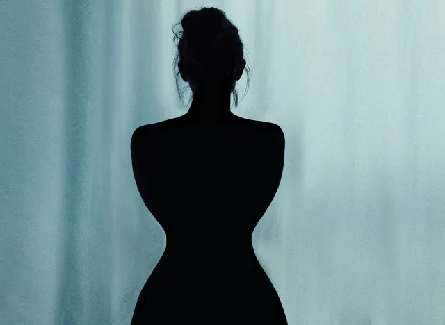 The beautiful silhouette of a young woman, hair in a knot. Hourglass figure. Blue background with curtains.