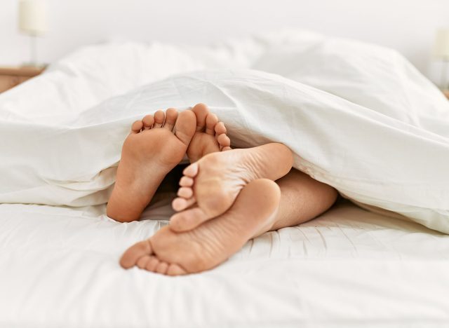 Couple feet under sheets on the bed at home.