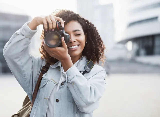 Woman photographer with dslr camera taking pictures outdoor. Mixed race girl with photo camera outdoor. Home hobby, lifestyle, travel, people concept