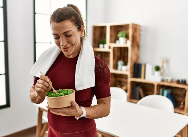 Middle age caucasian sporty woman eating salad at home.