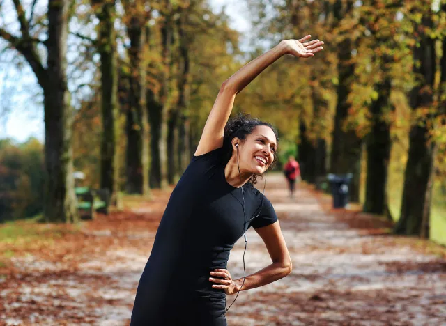 positive woman stretching outdoors preparing for exercise in sportswear