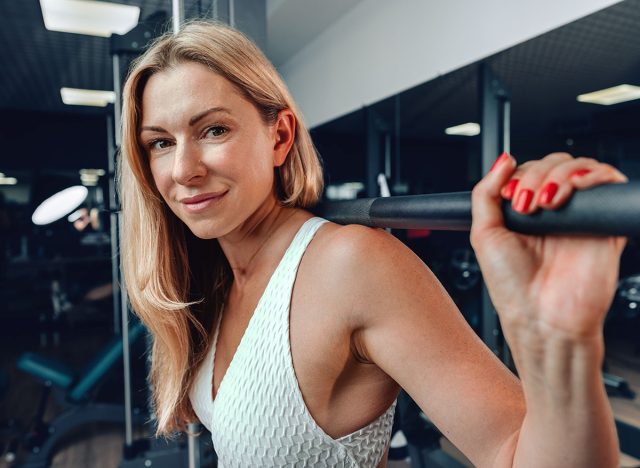 Middle-aged fitness woman doing squat exercise in a gym