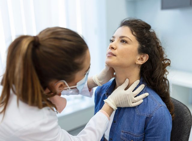 Endocrinologist examining throat of young woman in clinic. Women with thyroid gland test . Endocrinology, hormones and treatment. Inflammation of the sore throat