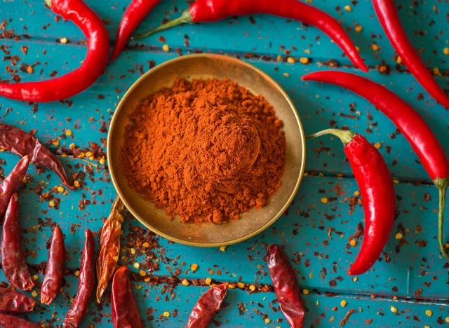 Chili powder and fresh and dried peppers on table background
