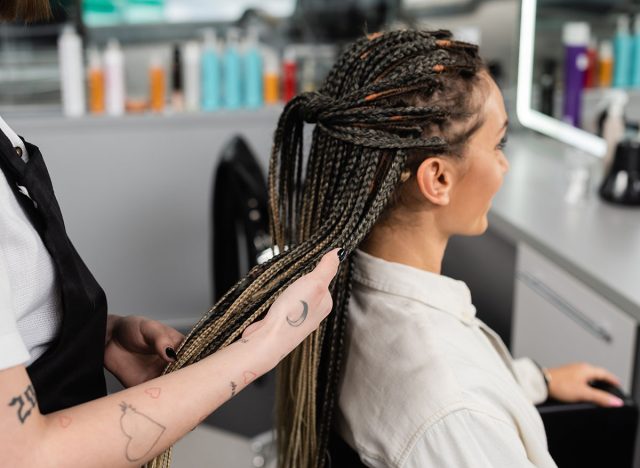 hair professional, tattooed beauty worker holding braids of female client in salon, beauty industry, salon job, customer in salon, hairdresser, salon services, hair make over