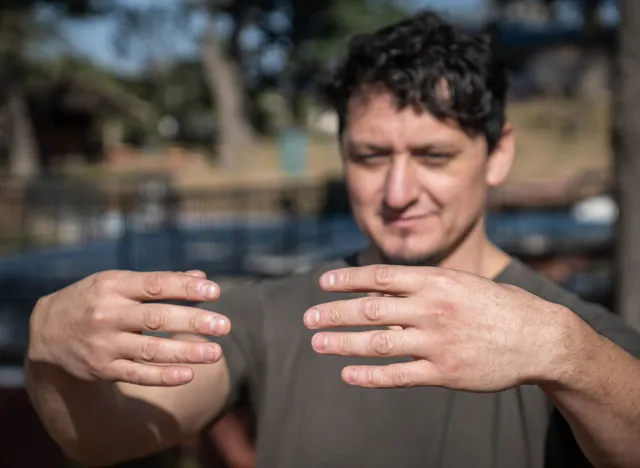 A middle-aged Caucasian man assumes the static posture of Tree Hugging, an essential technique in Chi Kung practice.