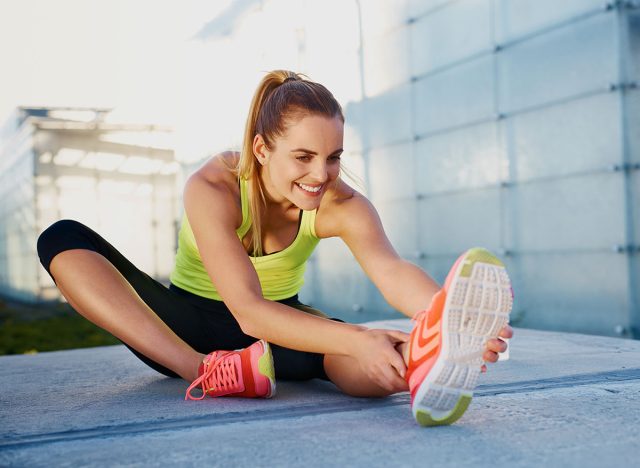 Happy young woman stretching before running outdoors