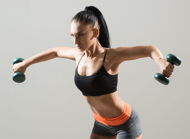 athletic woman pumping up muscles with dumbbells