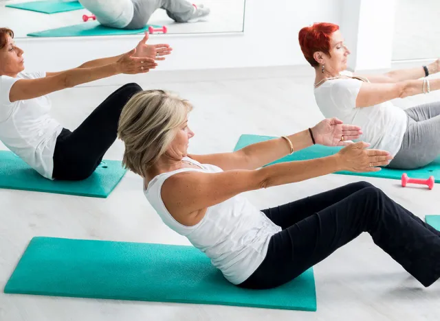 Group of middle aged women doing abdominal exercise in gym.
