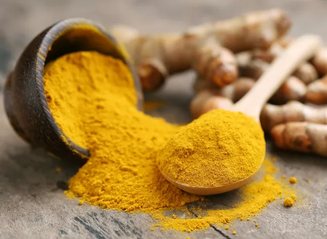 Turmeric powder and fresh turmeric on wooden background.