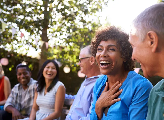 Group Of Mature Friends Socializing In Backyard Together