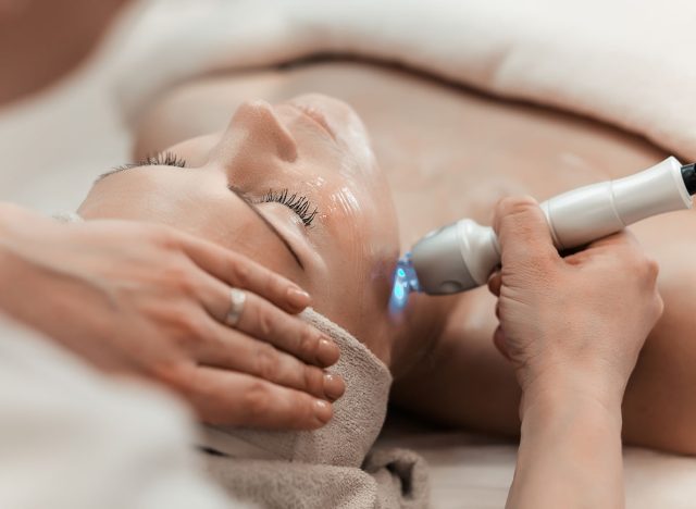 Woman getting laser and ultrasound face treatment in medical spa center, skin rejuvenation concept