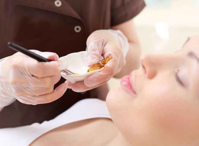 Chemical peeling, exfoliating treatment. Beautician imposes on the woman's face a cosmetic preparation.