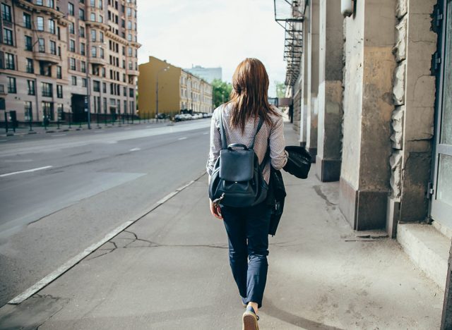 Back view of a hipster girl walking on city street