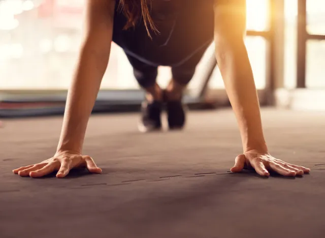 Close up woman hand doing push ups exercise in a gym in morning, sunlight effect.