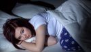 Woman laying on bed in night with her eyes opened.
