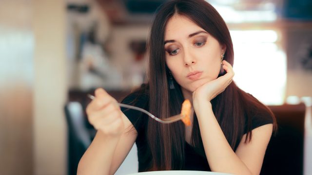 Female Customer Unhappy with the Dish Course in Restaurant. Depressed lonely woman suffering from appetite loss
