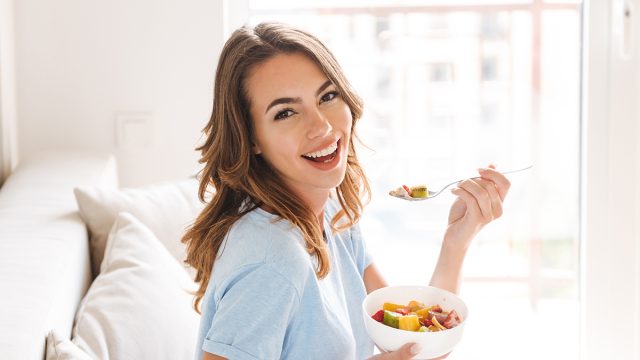 Cheerful,Young,Woman,Eating,Healthy,Breakfast,While,Sitting,On,A