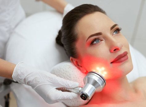 Facial Beauty Treatment. Woman Doing Red Led Light Therapy