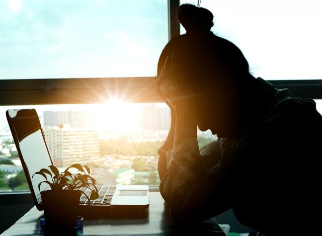 woman sitting down, his face unsettled. At the computer desk she has headaches and stress. Cause of hard work and insufficient rest.