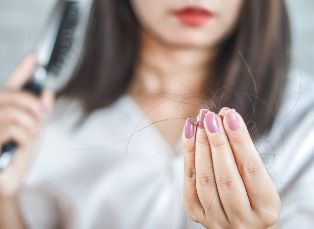 Woman's hand holding hair strands fallen on a comb in close-up