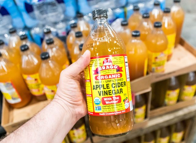 Los Angeles, CA/USA 07/20/2019 Shoppers hand holding a bottle of Bragg brand organic raw unfiltered apple cider vinegar in a supermarket aisle